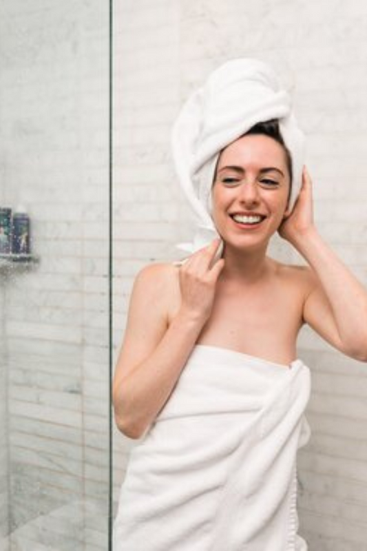 Happy-fresh-woman-in-white-towels-stepping-out-of-shower