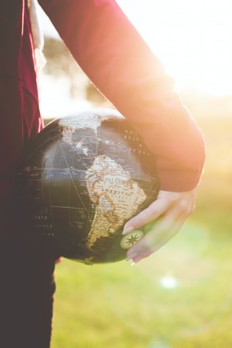 Unsplash/BenWhite-person-holding-globe-like-soccer-ball-facing-sunlit-field